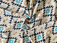 Load image into Gallery viewer, Organic Cotton Muslin Swaddle cloth with geometric Aztec print design in blue/black/gold. Cloth in twisted decorative layout.
