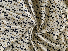 Load image into Gallery viewer, Organic Cotton Muslin Cloth Swaddle with black and gold bows varying sizes on white. Cloth is twisted decoratively to show pattern.
