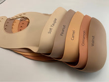 Load image into Gallery viewer, Silicone Bib BPA Free in light brown/camel colour and 4 buttons with large crumb catcher scoop. Displayed with other similar colours for comparison.
