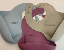 Load image into Gallery viewer, Silicone Bib BPA Free in a medium grey colour and 4 buttons with large crumb catcher scoop. Displayed with other colours for comparison.
