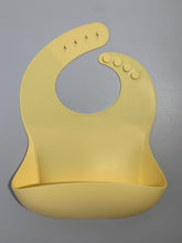 Load image into Gallery viewer, Silicone Bib BPA Free in a light pastel yellow colour and 4 buttons with large crumb catcher scoop.
